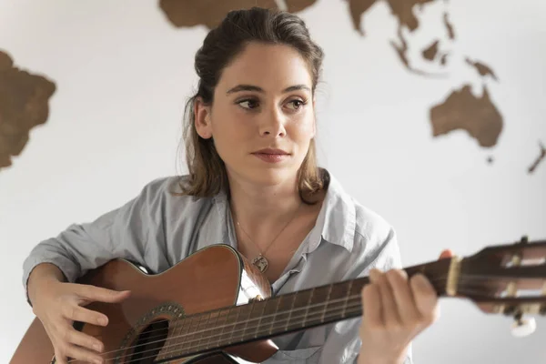 Çekici genç kız odasında gitar çalıyor..