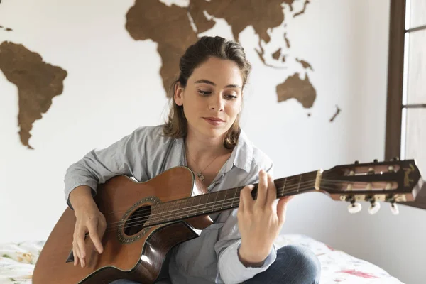 Çekici genç kız odasında gitar çalıyor..