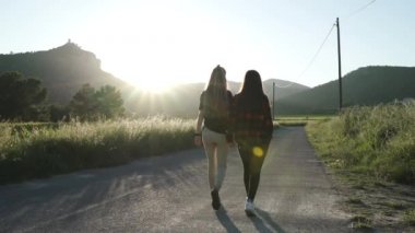 Lezbiyen kızlar gün batımının altında dağda geziniyorlar. LGBT