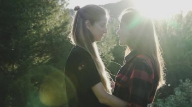 Lezbiyen kızlar gün batımında sarılıp öpüşüyor. LGBT