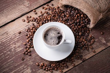 Kahve fincanı ve fasulye ahşap bir masada..