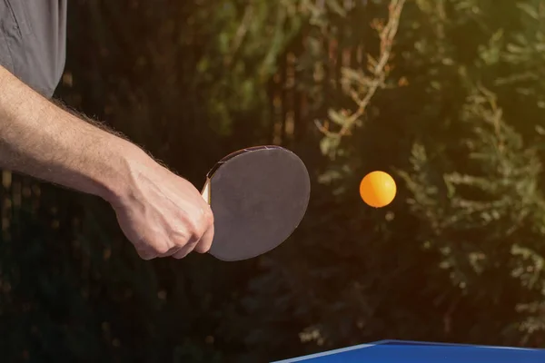 A man playing table tennis, ping pong outside in the garden.