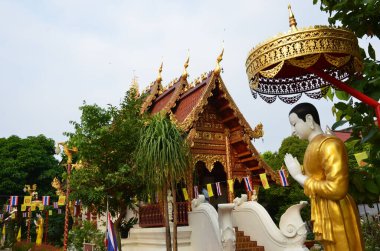Chiang Rai 'deki güzel Wat Phra Singh tapınağının önünde dua eden heykel.
