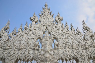 Buda imajına sahip inanılmaz bir heykel ve ejderhalar Chiang Rai 'deki güzel beyaz tapınak Wat Rong Khun' un köprüsüne hükmediyor.