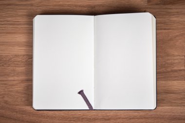 Kahverengi ahşap bir masa üstünde açık defter beyaz sayfalar