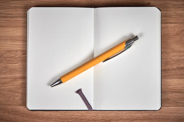 Open notebook and ballpoint on a brown wooden table — Stock Photo, Image