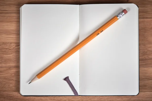 Caderno aberto e lápis amarelo em uma mesa de madeira marrom — Fotografia de Stock