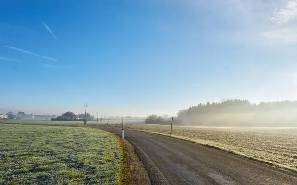 Brouillard matinal sur une route à travers les champs — Photo