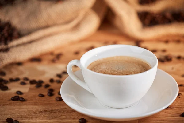 Kopp kaffe med bönor på bordet — Stockfoto