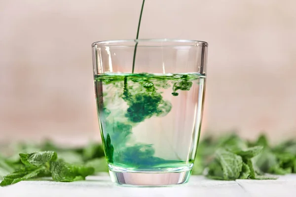 Dissolving liquid chlorophyll in glass of water Stock Image