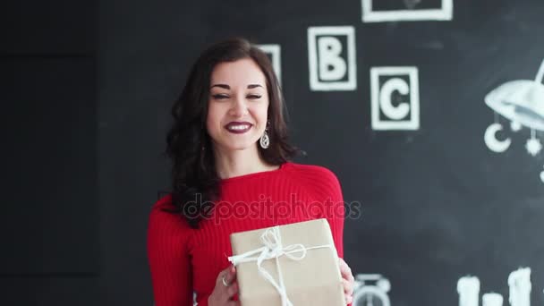 Una hermosa chica ha recibido un regalo para la Navidad o un cumpleaños. Ella es feliz y sonriente. es divertido, carismático y atractivo . — Vídeos de Stock