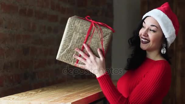 Hermosa chica Santa Claus recibió un regalo en Navidad. Ella está sonriendo y tonteando. es divertido, carismático y atractivo. Año Nuevo . — Vídeo de stock