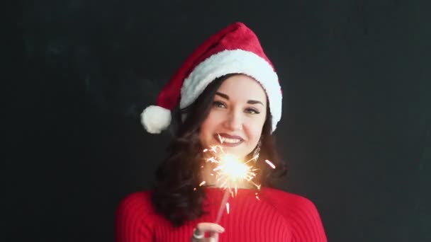 Menina bonita Papai Noel Segurando um Natal Sparkler e sorrisos. Ela é muito bonita e atraente. Ano Novo . — Vídeo de Stock