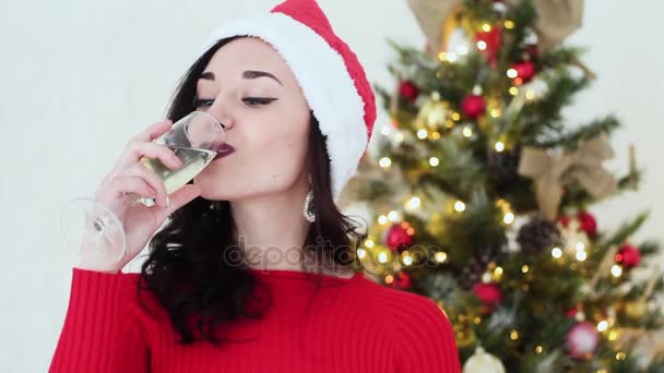 Hermosa chica Santa Claus bebiendo champán y sonriendo. Ella es muy hermosa y atractiva. Año Nuevo 2017 . — Vídeo de stock