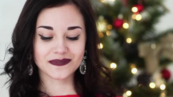 Belle fille souriant tout en se tenant à côté de l'arbre de Noël pour la nouvelle année. Elle est très belle et attrayante. Gros plan . — Video