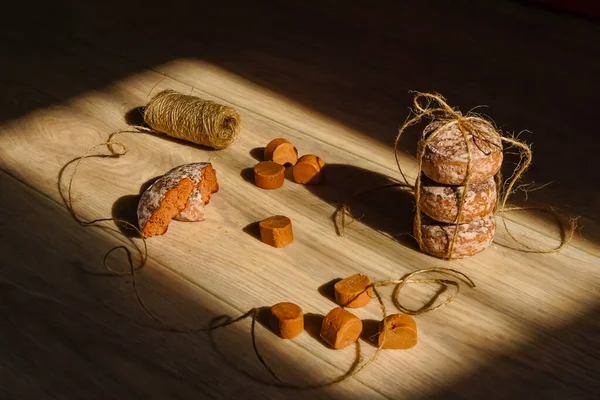 Zencefilli kurabiyeler, tatlılar, hafif ahşap bir yüzeyde jüt kablosu. Güneş ışığı kompozisyonda güzel bir çizim sağlar. Evde çay için lezzetli yemekler var..