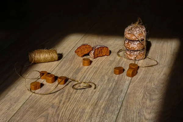 Güneş ışığındaki kokulu zencefilli kurabiyeler ve şekerler, açık ahşap bir yüzey üzerinde doğal kordonla. Güzel kompozisyon