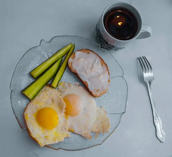 Kızarmış yumurta, taze salatalık, kahvaltıda peynirli sandviç ve çay. Aile masada, hep birlikte. Beyaz masa üstü ve lezzetli sıcak yiyecekler. Sabah atıştırması
