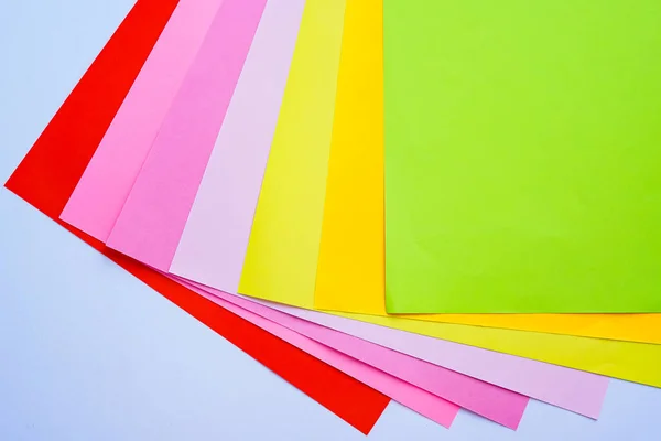 Parlak renkli ofis kağıtları beyaz arka planda yukarıdan yakın plan çekilir. Kırmızı, pembe, mor, sarı, turuncu, yeşil