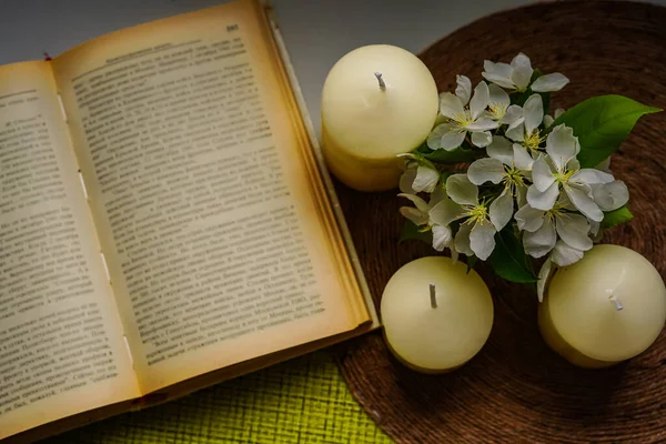 On the windowsill is an open book and flowers of apple trees and candles. Spring is a time of good books, inspiration and dreams. Image taken from above.