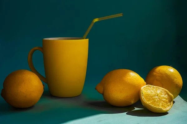 Üç buçuk limon, mavi zemin üzerinde limonata olan sarı bir kupa. Virüs ve hastalıkların önlenmesi için doğal vitamin kaynağı.