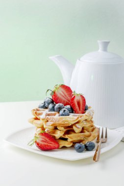 Yaban mersinli ve dilimlenmiş çilekli bir yığın lezzetli waffle.