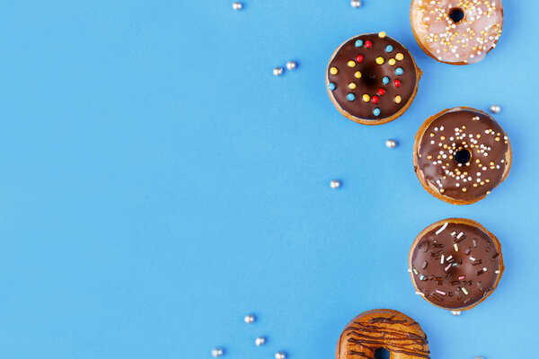 For sweet tooth. Yummy glazed assorted doughnuts on pastel color blue background on the right side.Top view. Copy space