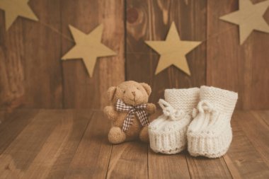 Çok tatlı! El yapımı bebek ayakkabıları ve retro Syle 'da ahşap arka planda küçük kahverengi ayı. Metin için boşluk