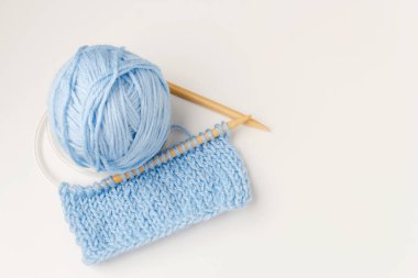 Yün iplikleri, tığ işi, örgü iğneleri, beyaz arka planda mavi renkli. Boşluğu kopyala