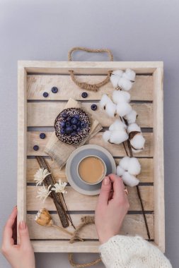 Yammy! Tahta servis tepsisinde bir fincan kahve ve yabanmersinli çörek, sabah konsepti, pamuk çiçekli üst manzara.