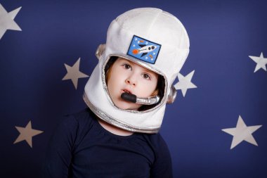 Astronot gibi giyinmiş, gülümseyen küçük kız.