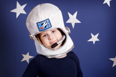 Astronot gibi giyinmiş, gülümseyen küçük kız.