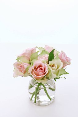 Pembe gül buketini beyaz vazoda cam güllerle kapatın..
