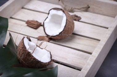 Kırık hindistan cevizi, ahşap tepsi arka planında. Tahta tepsi, hindistan cevizi ve palmiye yaprağı. Tropik Meyve.