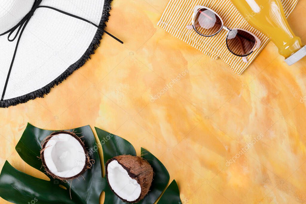 Summer vacation concept flat lay. Palm leaf and half of the coconut with summer hat, sun glasses, juice bottle on yellow decorated background.