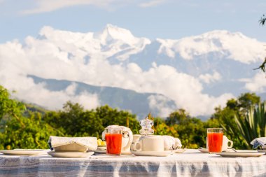 Annapurna sıradağlarının önünde giyinmiş kahve, çay ve karpuz suyu ile kahvaltı masası, Himalayalar, Nepal
