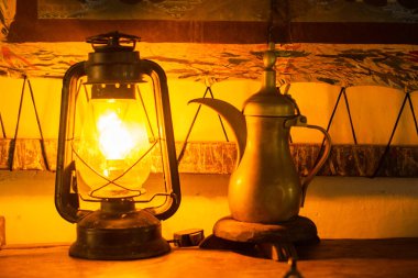 Elektrik ampullü bir gaz lambası eski tarz bir çaydanlığa ışık tutuyor..