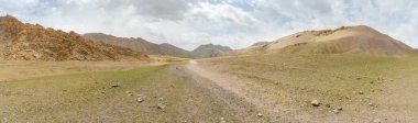Hindistan 'ın Ladakh bölgesindeki Leh bölgesinde köy ve kaya oluşumuyla, Himalayalar' daki dağları ve tepeleri aşan bir düzlükte yürüyüş patikası.