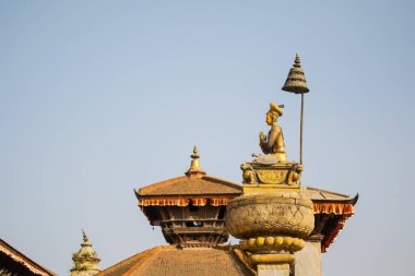Nepal, Bakhtapur 'daki Durbar Meydanı' nda, tapınak çatıları ve şemsiyenin altında altın figürlü adak sütunları var..