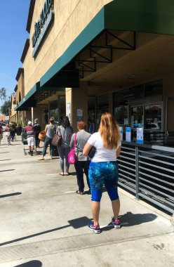 PASADENA, CALIFORNIA, ABD - 31 Mart 2020: Maske ve eldiven giyen müşteriler, Covid Corona Virüsü salgını nedeniyle karantina sırasında Whole Foods 'dan alışveriş yapmak için uzun kuyruklarda veya kuyrukta beklerler.