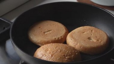 Hamburger yapmak için sıcak tavada ızgara ekmek.