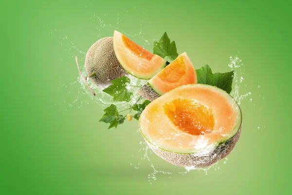 Wasser spritzt auf Scheiben japanischer Melonen auf grünem Hintergrund — Stockfoto