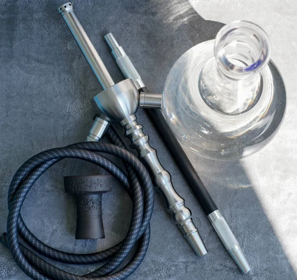 stock image Steel hookah shisha with flask, mouthpiece and clay bowl, tobacco on a gray concrete background.