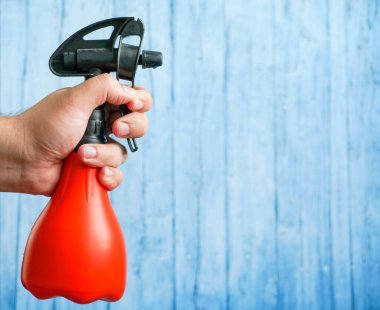 Mavi arka planda erkek eli olan bitkiler için sprey..