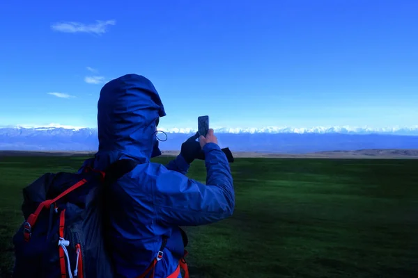 Bir telefon kamerasının yardımıyla erkek turist fotoğraflarının dikiz görüntüsü bir kamp turundaki dağın manzarası. Fotoğraf çekmek için bir telefon yardımıyla dolaşan bir adam. Koşun!.