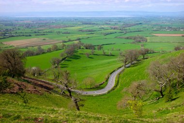 Severn Nehri 'ne doğru panoramik bir manzara ön planda dolambaçlı bir yol, Coaley Tepesi bakış açısı, Gloucestershire, İngiltere