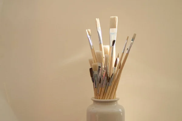 Artists paint brushes in pot on white background