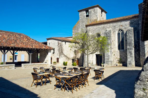 Restaurant tables prepared for lunchtime in the square in Pujols, Lot-et-Garonne, France. This historic fortified village stronghold is now a member of \