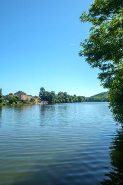 Penne d 'Agenaise' in eski nehir limanı Port de Penne 'deki sakin nehir parkı boyunca güneşli bir yaz sabahı, Lot et Garonne, Fransa