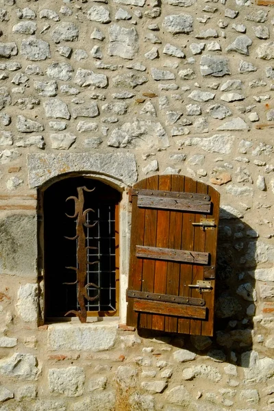 法国罗得加隆的普约斯 一个用华丽的安全栅栏装饰在石墙上的生气勃勃的紧闭窗户 这个历史名村是 Les Beaux Villages France 协会的成员 — 图库照片